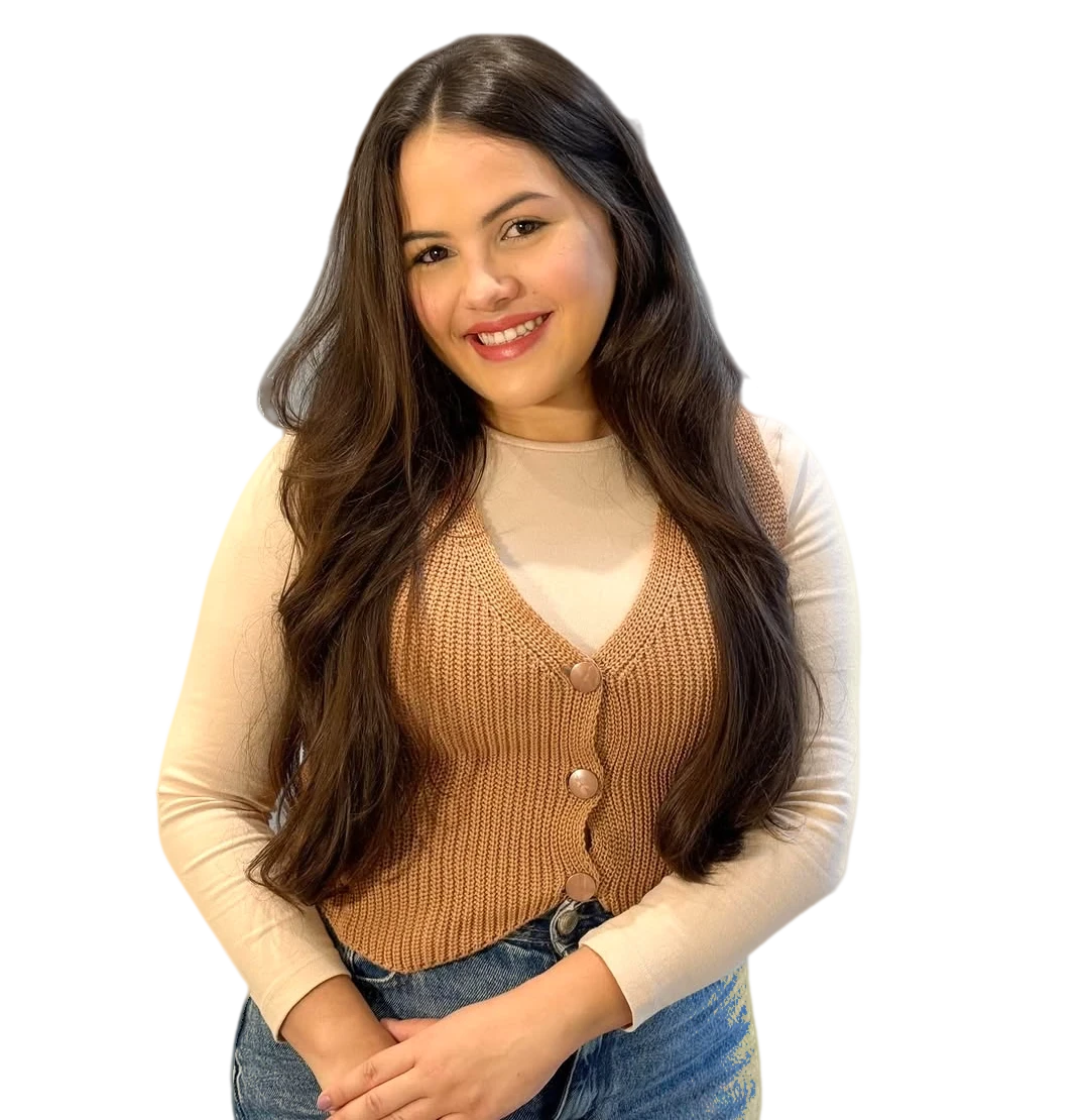 Yasmim Albuquerque sorrindo, de colete caramelo de tricô, com as mãos juntas