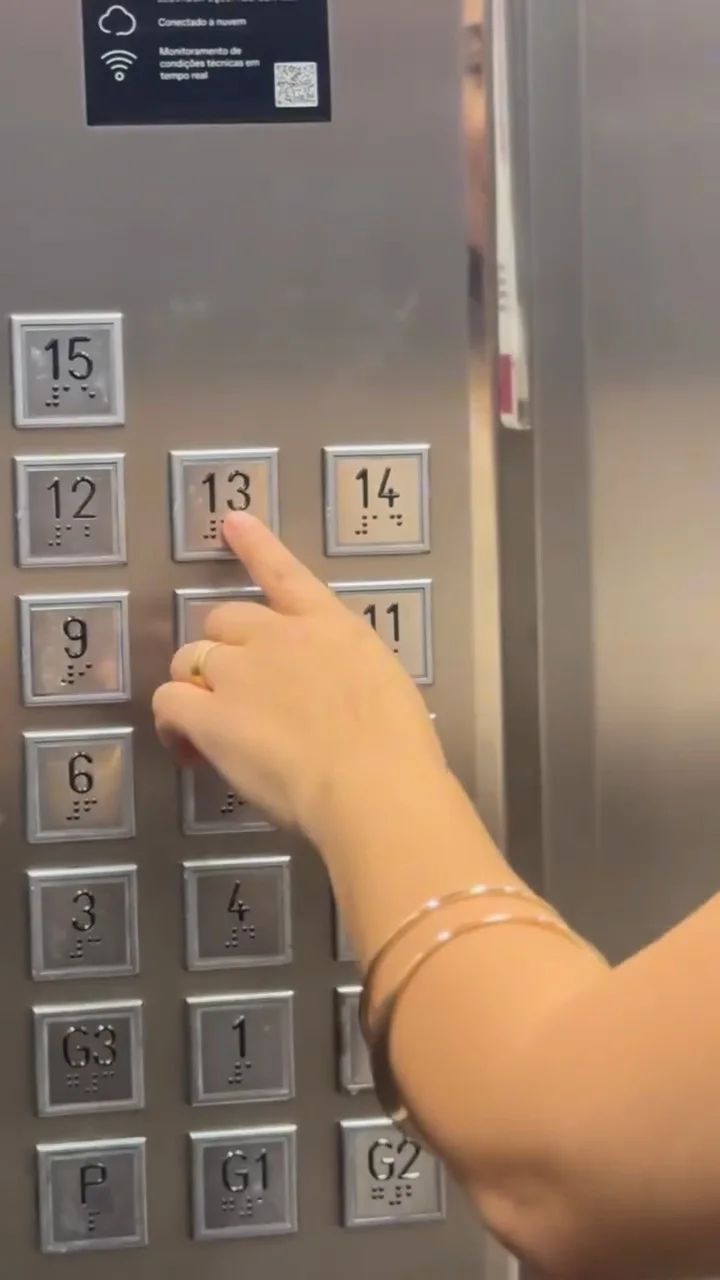 Painel do elevador com o dedo apertando o botão 13