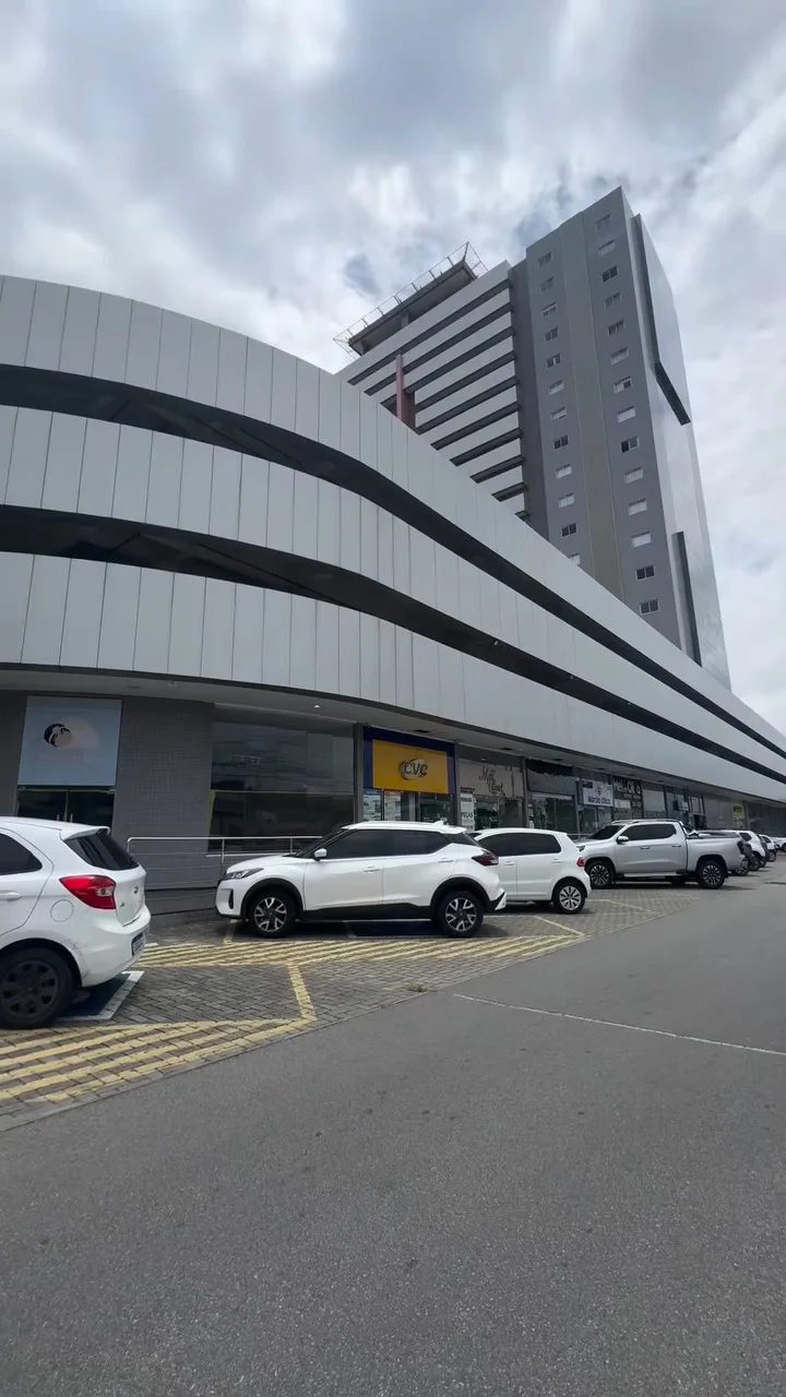 Fachada do Empresarial Humberto Lobo, prédio alto de vidro em dia nublado